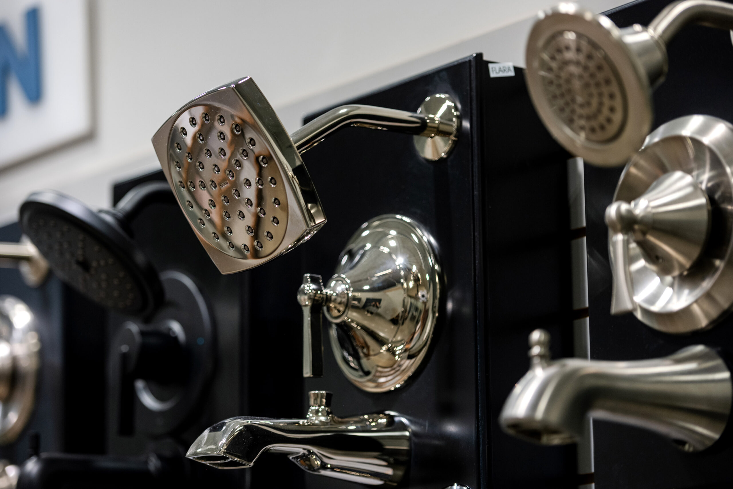Close-up of various showerheads and faucets in different shapes and finishes displayed on a wall in a showroom—perfect inspiration for your next bathroom renovation or bath remodel.